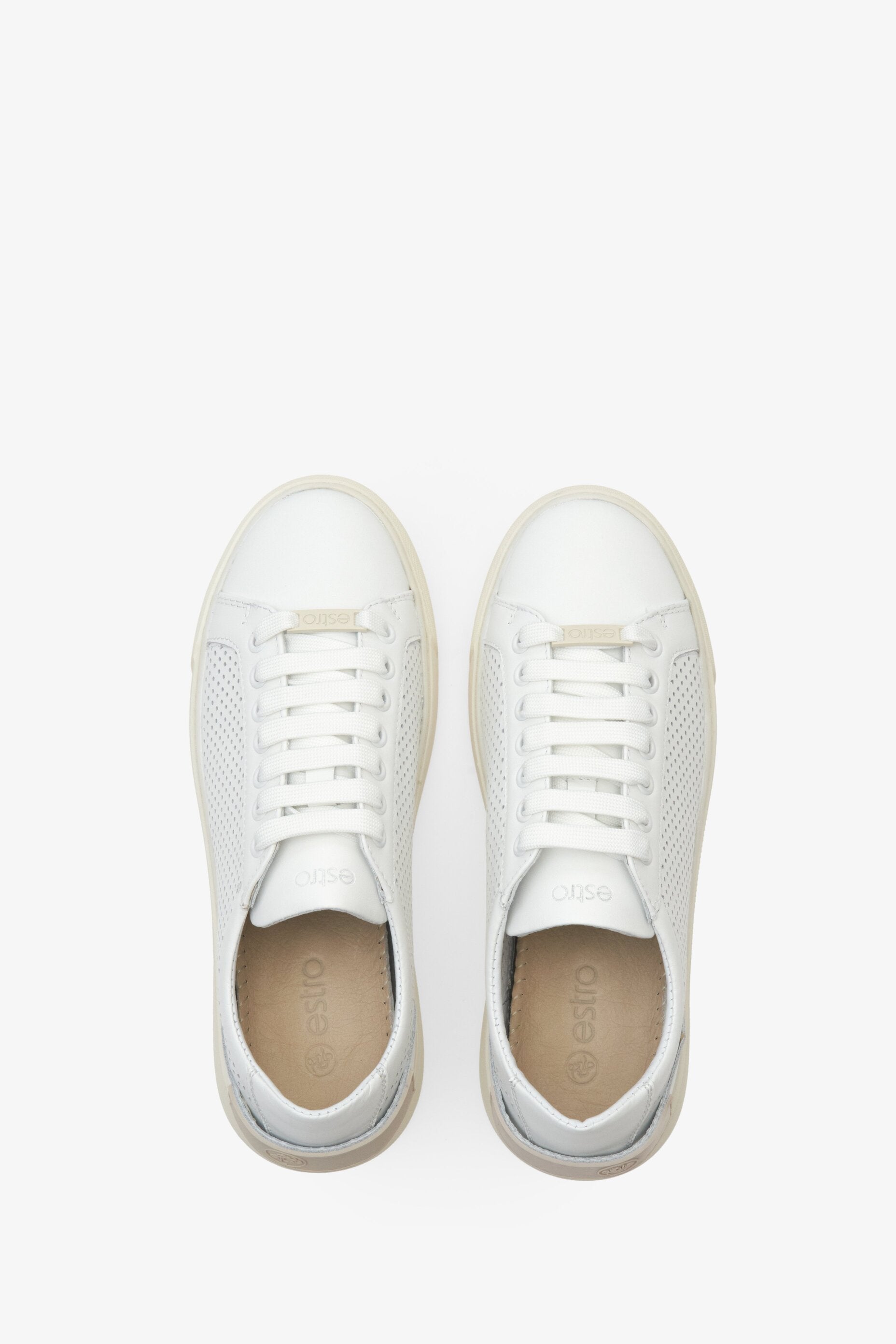 Women's white leather sneakers with perforation - presentation of the footwear from above.