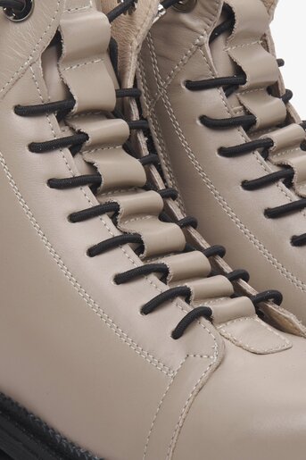 Women's beige winter boots made of genuine leather - close-up on the lacing.