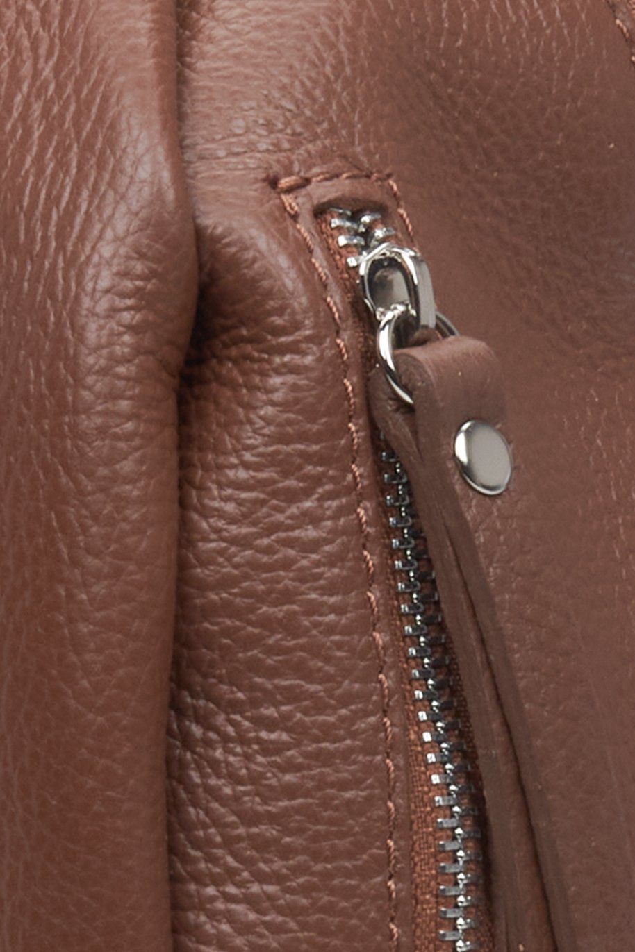 Elegant women's brown leather backpack with silver accents - close-up on details.