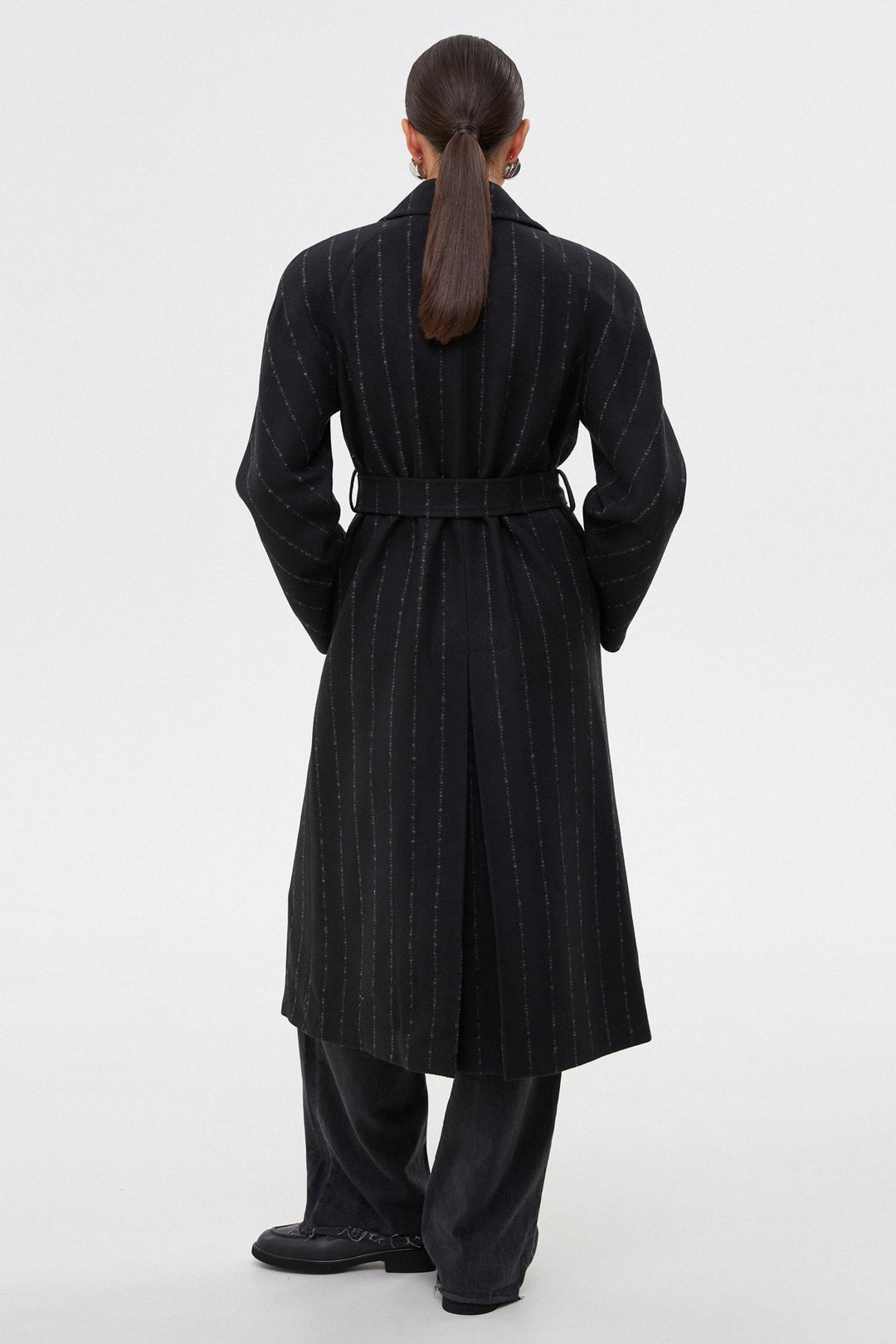 Black knee-length women's pinstripe coat by Estro - presentation of the model from the back.