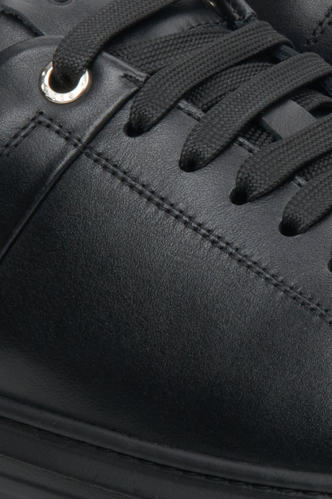 Low, black Estro men's sneakers with lacing - close-up on the heel and side line.