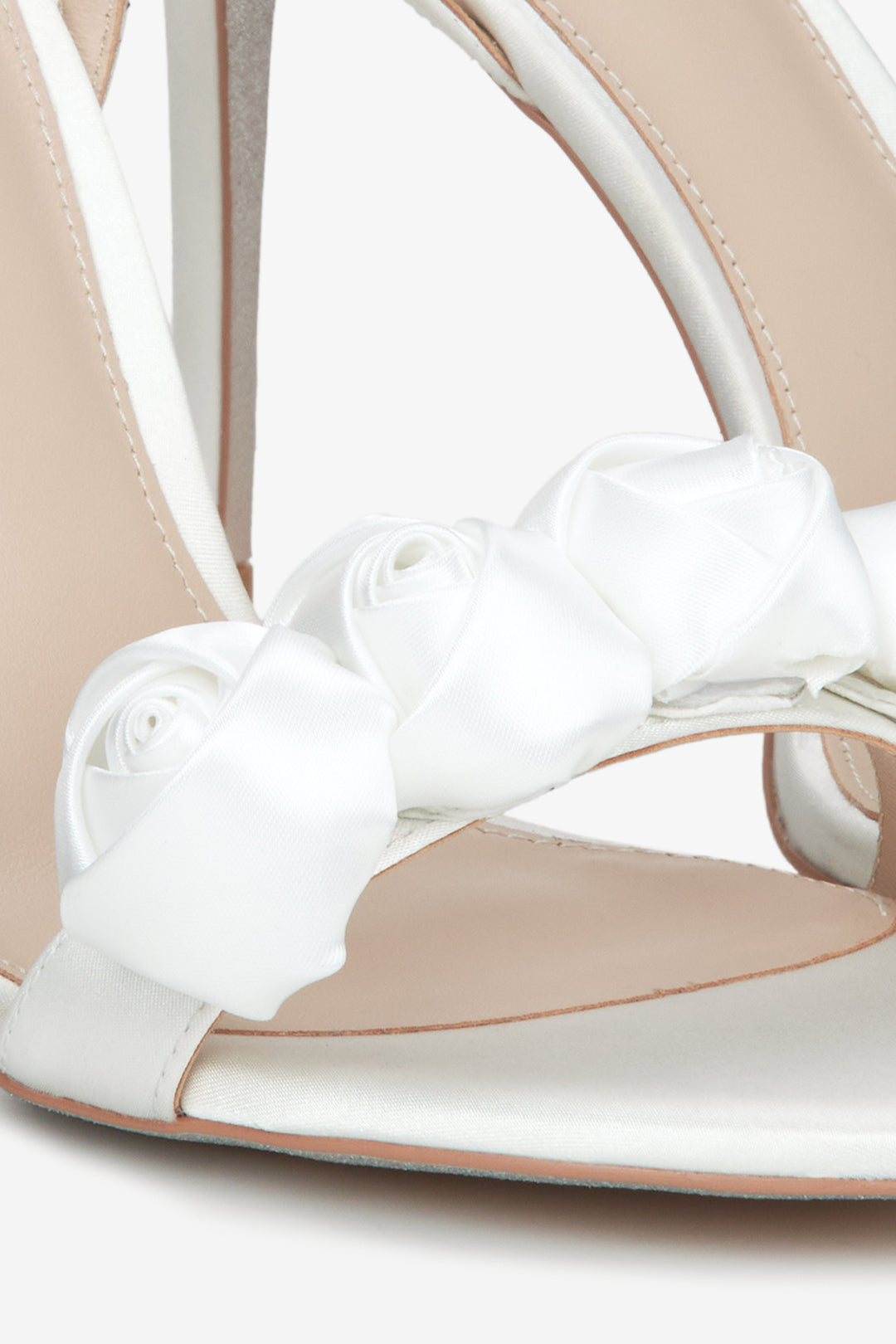 Women's white high-heeled sandals - close-up on the ornament.