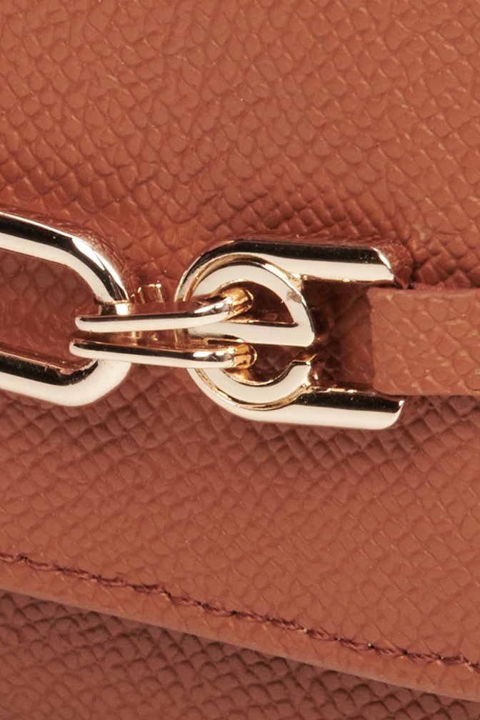 Women's brown leather small wallet with a gold clasp - close-up on details.