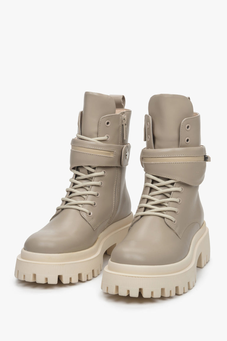 High Estro women's boots made of genuine leather in beige color with laces, zipper, and decorative strap - close-up on the front of the shoes.