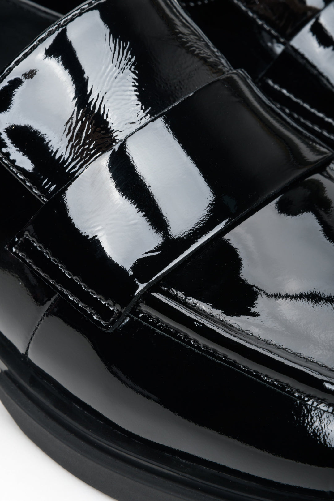 Women's black patent leather moccasins by Estro - close-up on details.