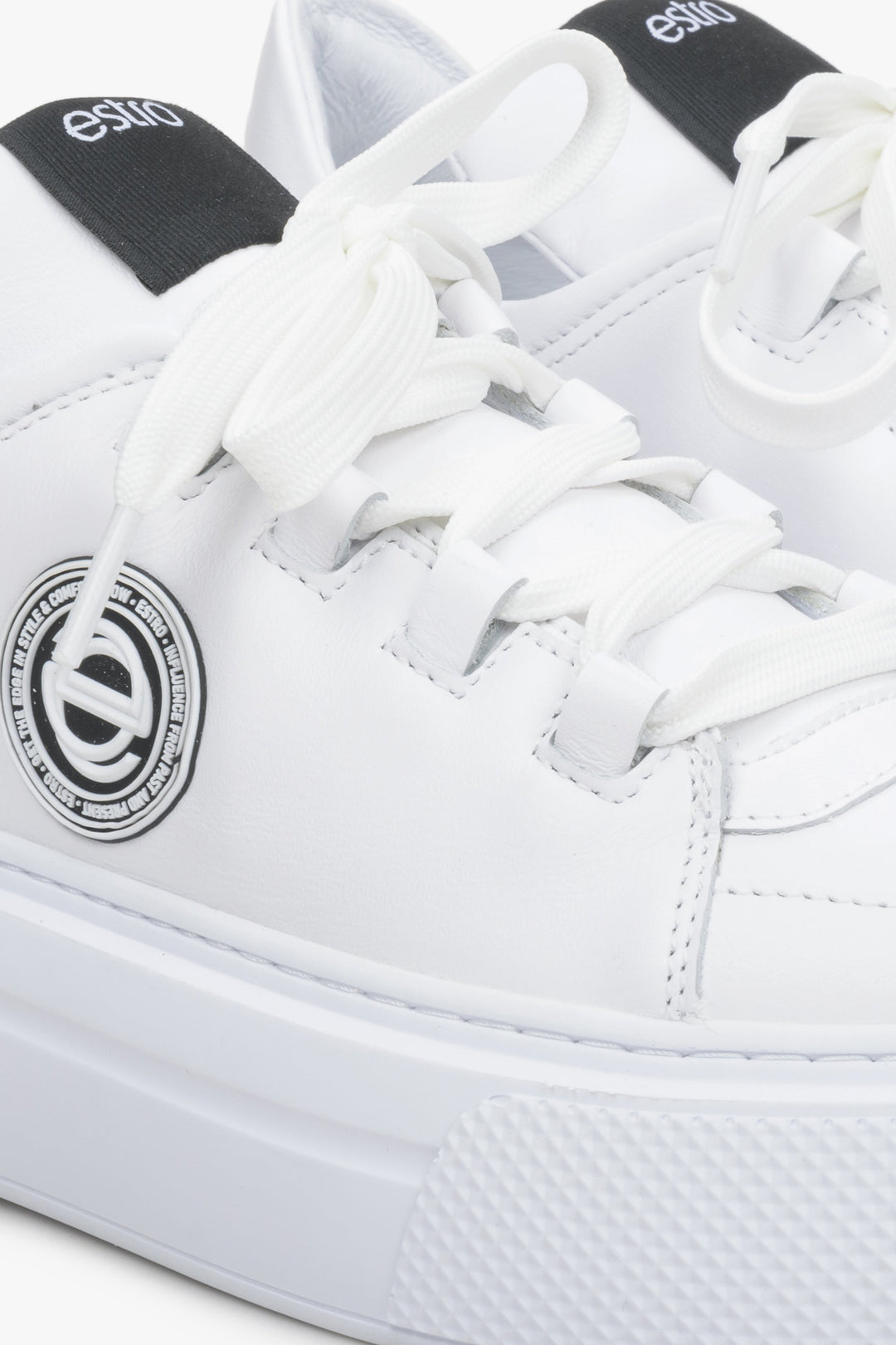 Women's white sneakers made of genuine leather - close-up on details.