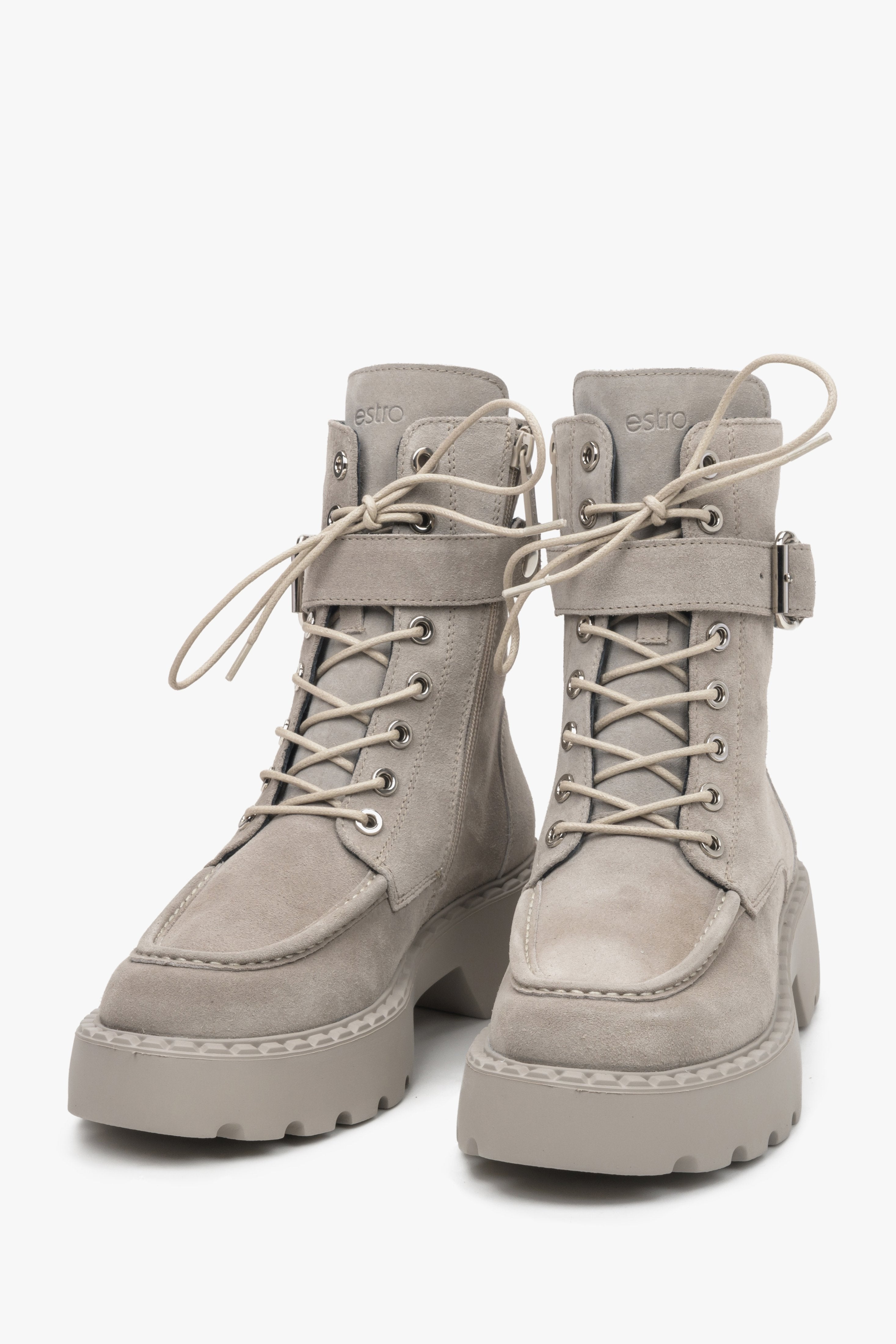 Grey women's work boots by Estro made from natural velour with laces and a zipper, as well as a decorative buckle - close-up on the front of the shoe.