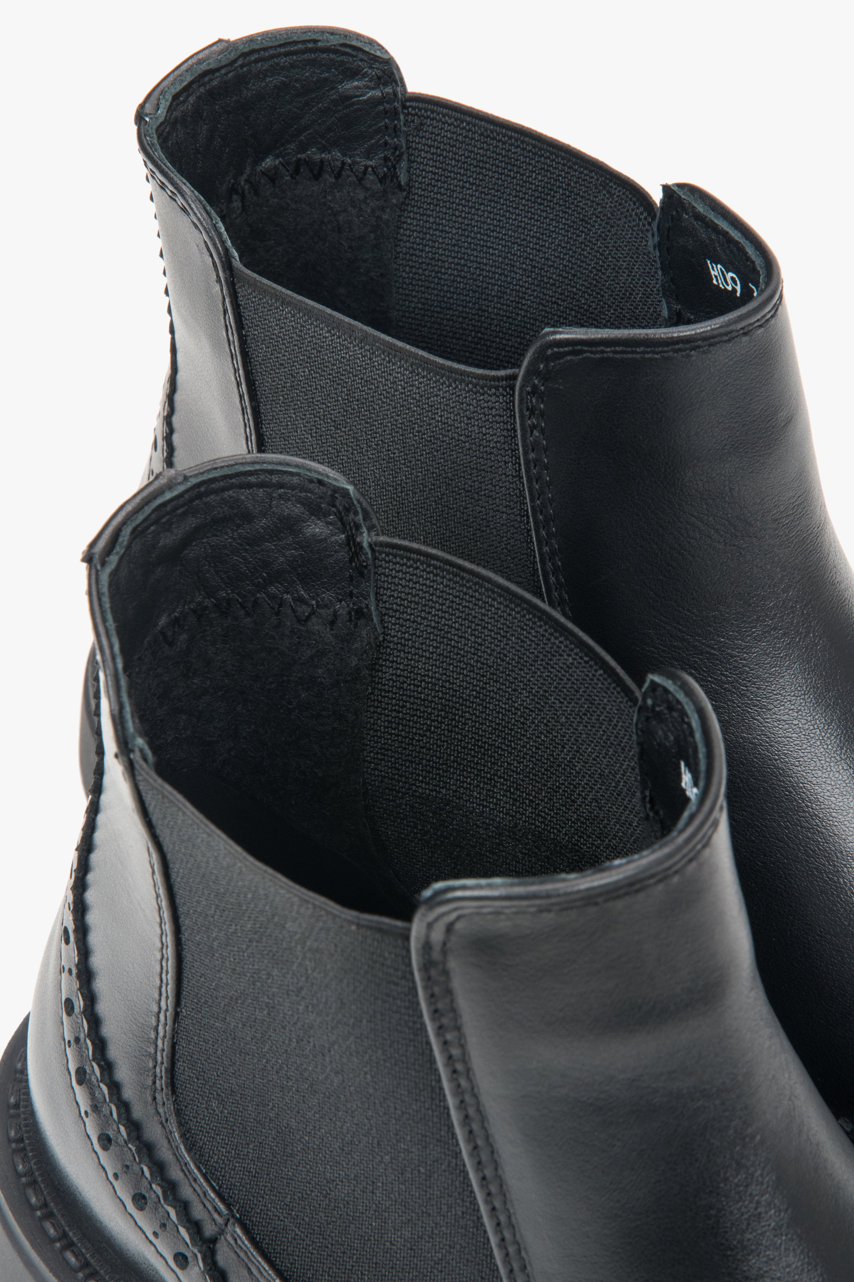 A pair of women's short black Chelsea boots with decorative perforations on the Italian leather upper.