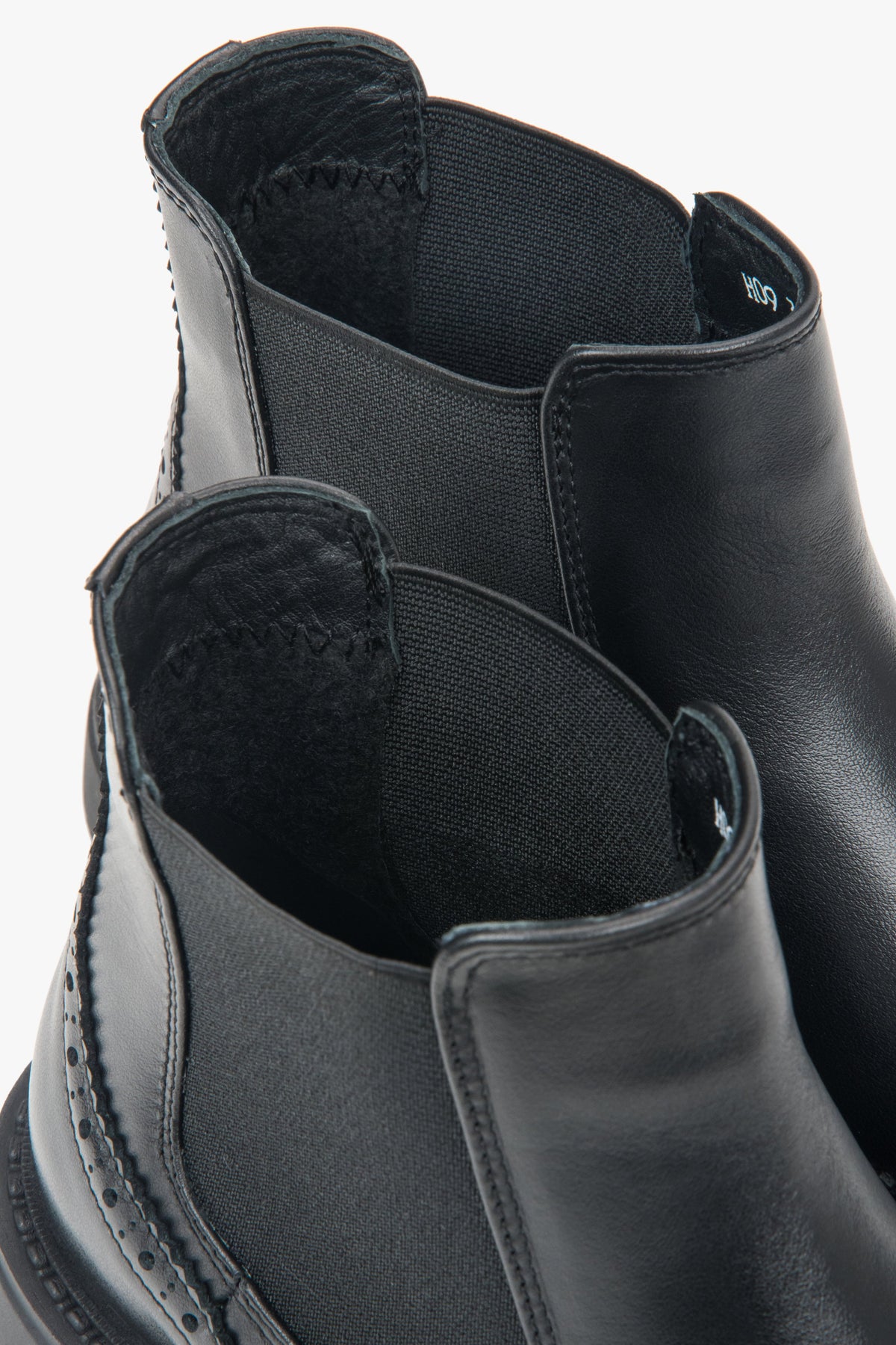A pair of women's short black Chelsea boots with decorative perforations on the Italian leather upper.