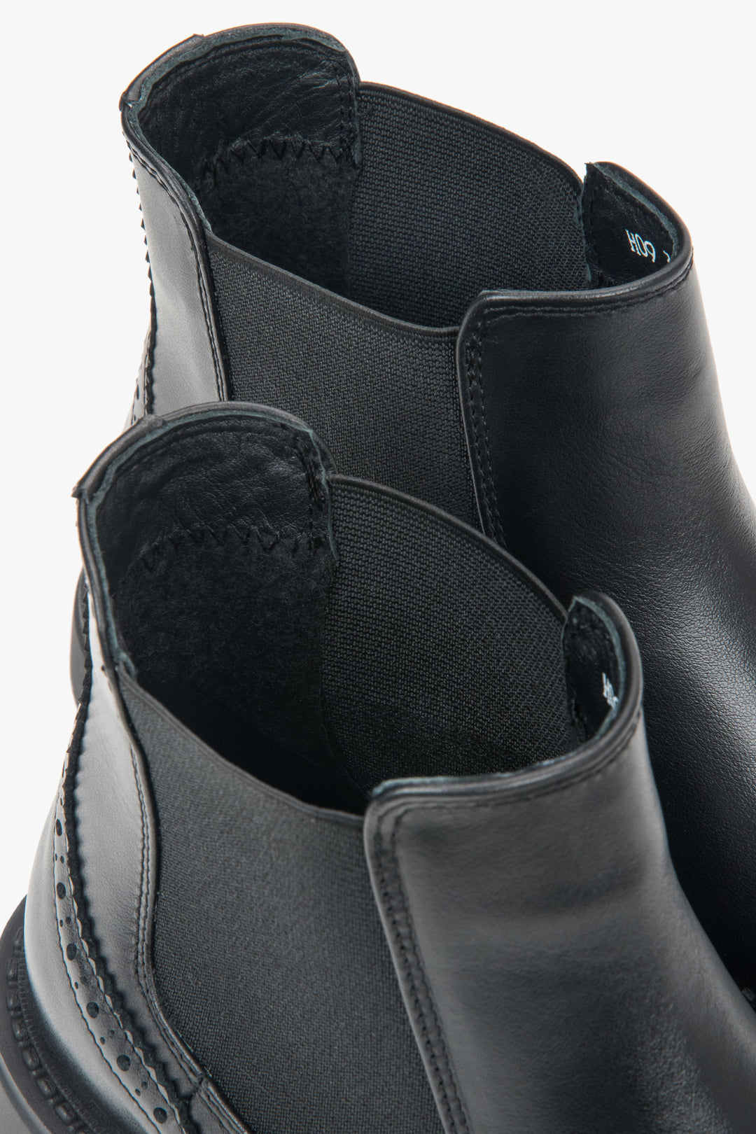 A pair of women's short black Chelsea boots with decorative perforations on the Italian leather upper.