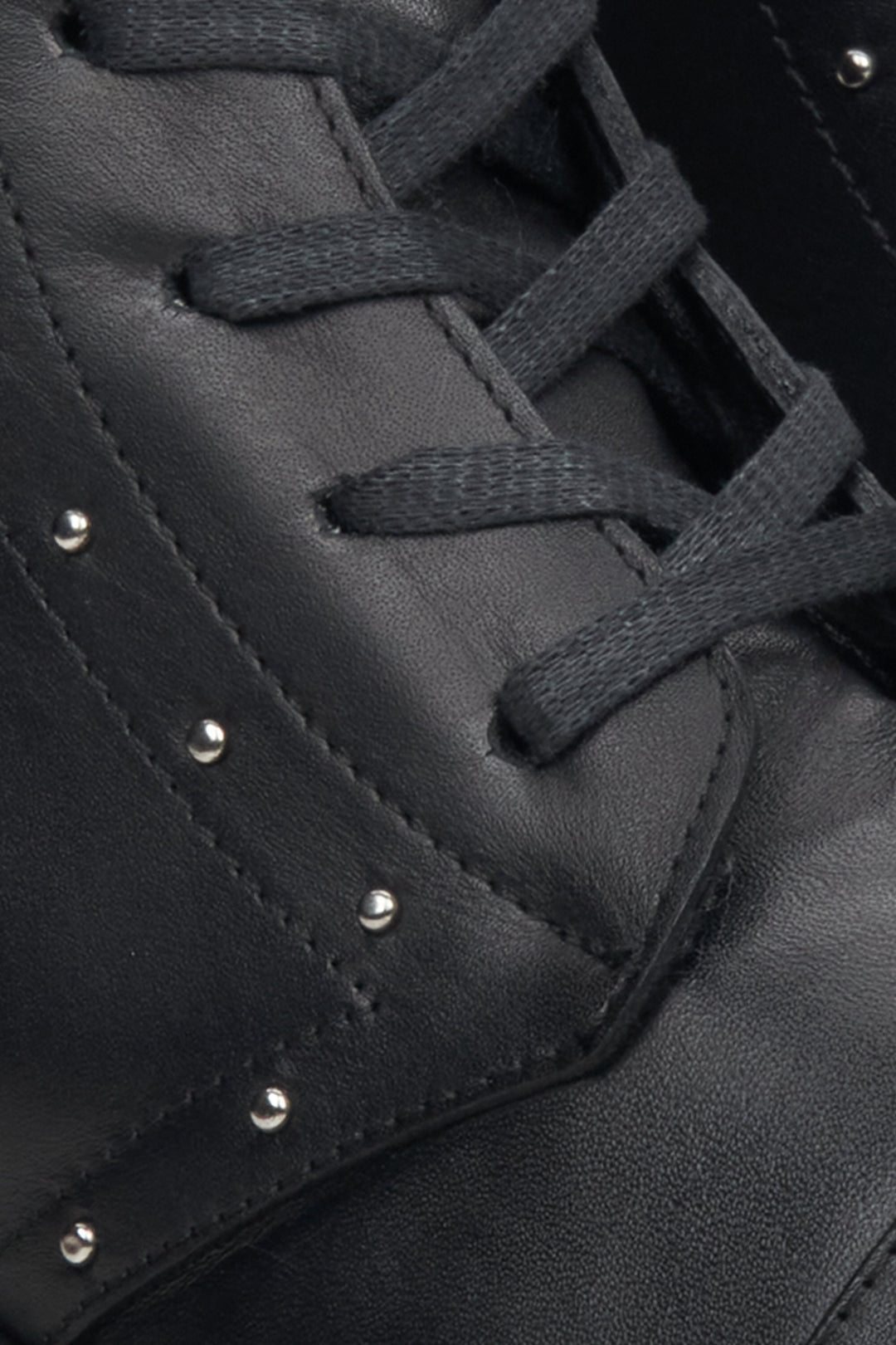 Black leather ankle boots Estro - a close-up on decorative lacing and silver studs.