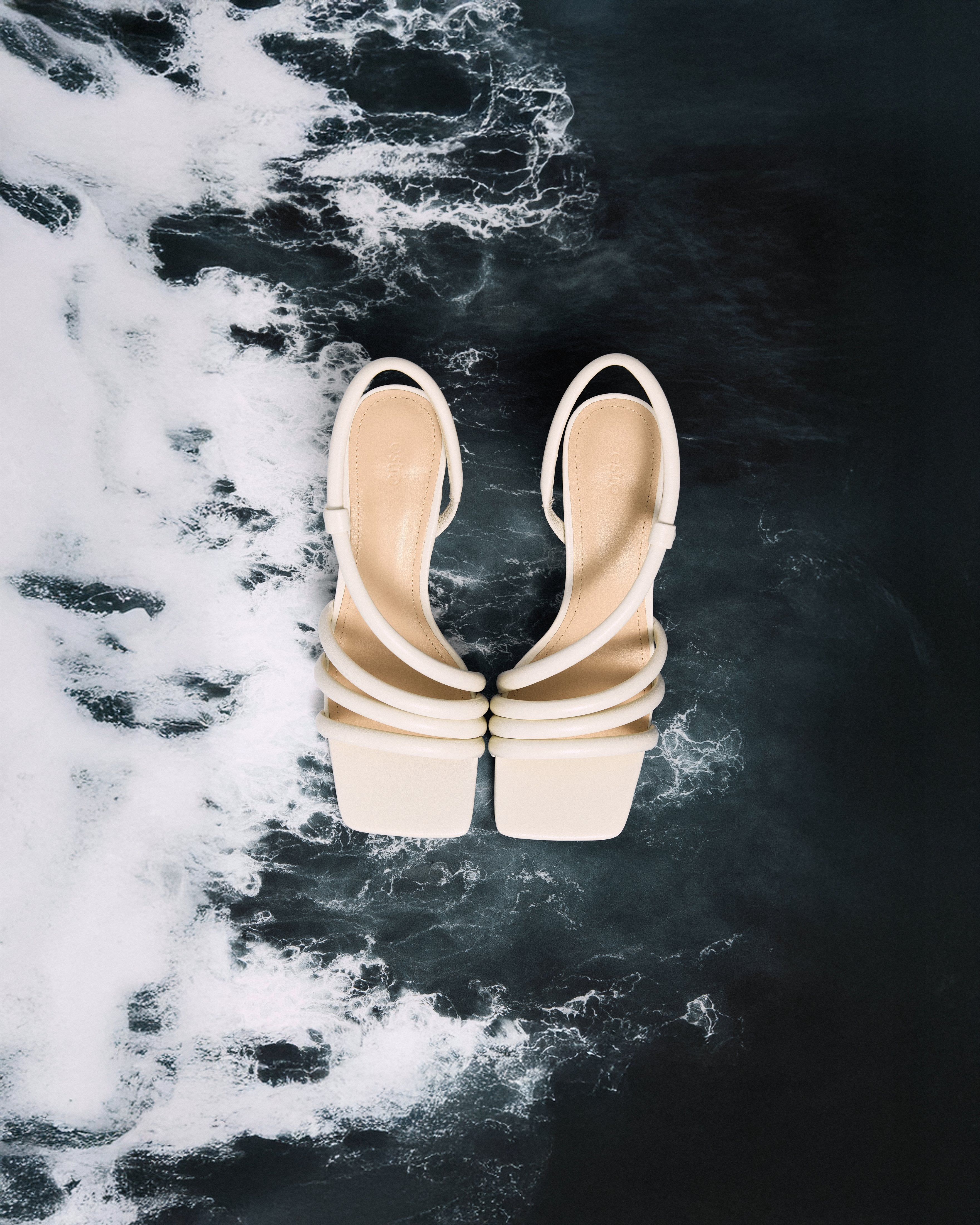 A top view of the pair of slip-on sandals, highlighting the luxury genuine chevro leather insole with a subtly embossed Estro logo.