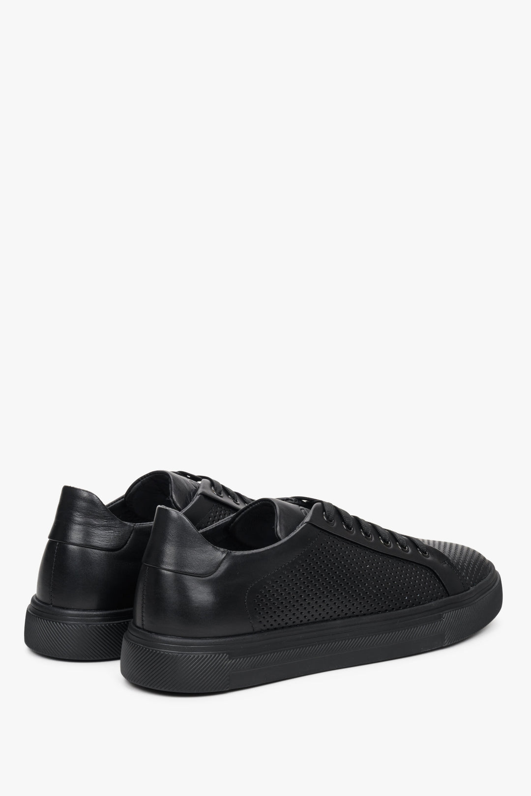 Men's black sneakers made of genuine leather with perforations - close-up of the heel and side seam of the shoe.