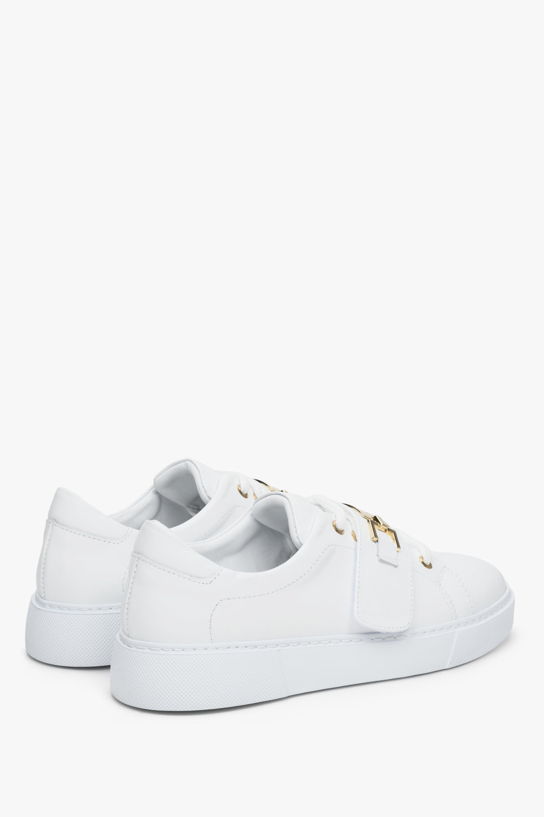 Women's white leather sneakers by Estro with a gold embellishment - close-up on the heel and side seam of the shoes.