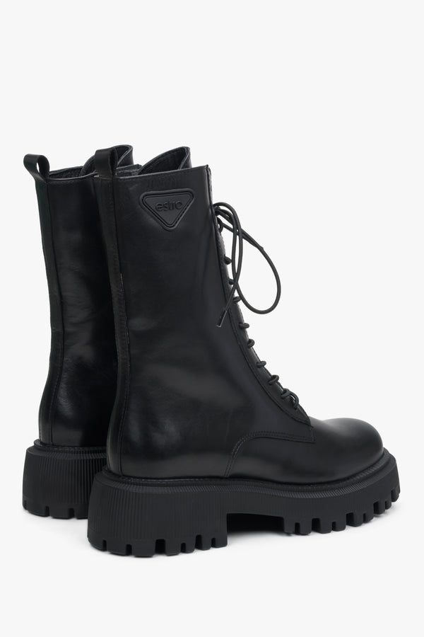 Women's Black leather ankle boots with a high shaft and decorative lacing system - close-up of the side seam and heel of the shoes.