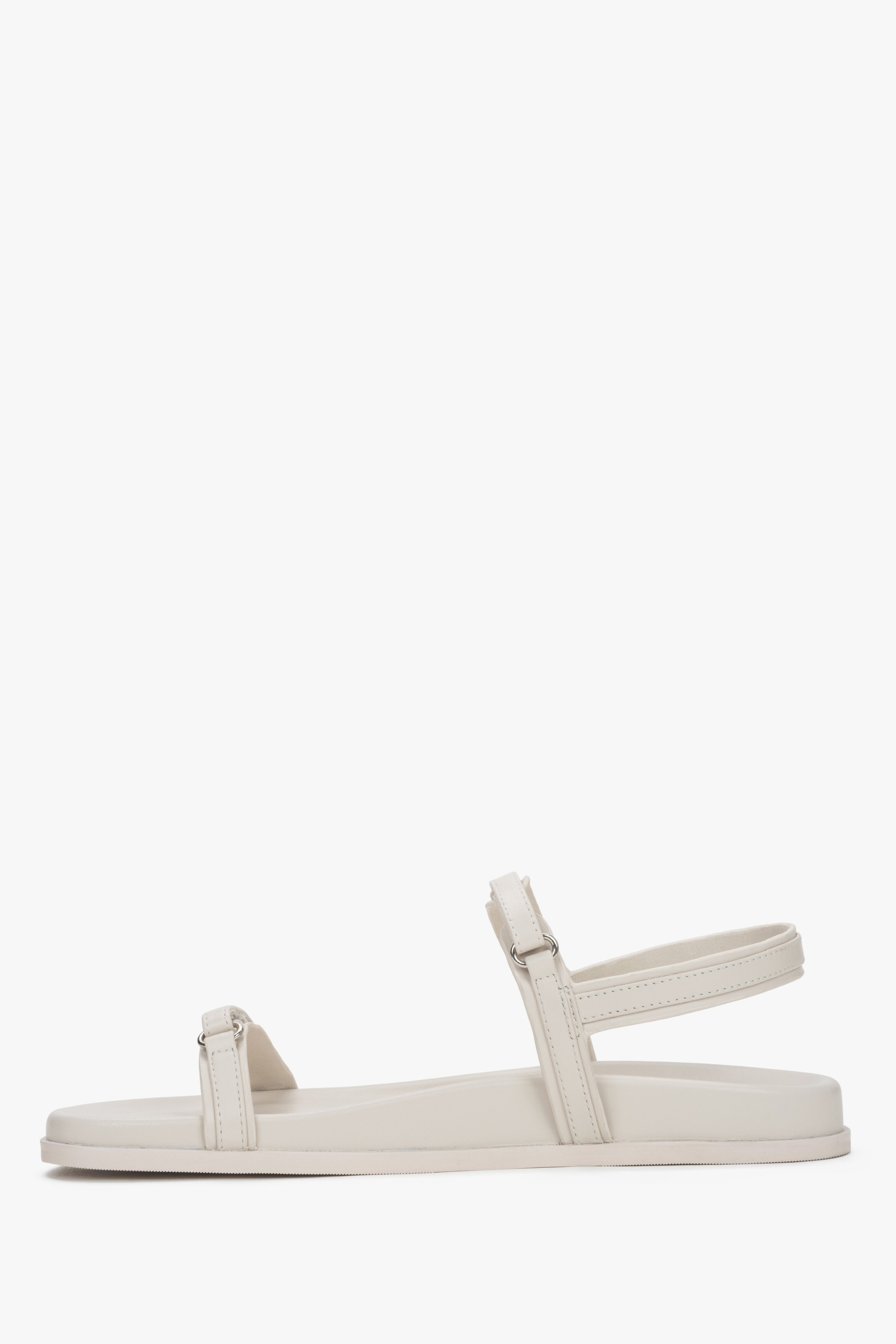 A pair of women's flat sandals constructed from genuine leather in a soft off-white shade.