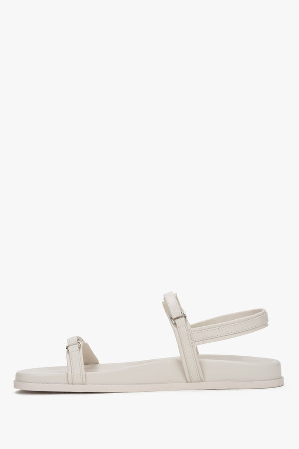 A pair of women's flat sandals constructed from genuine leather in a soft off-white shade.