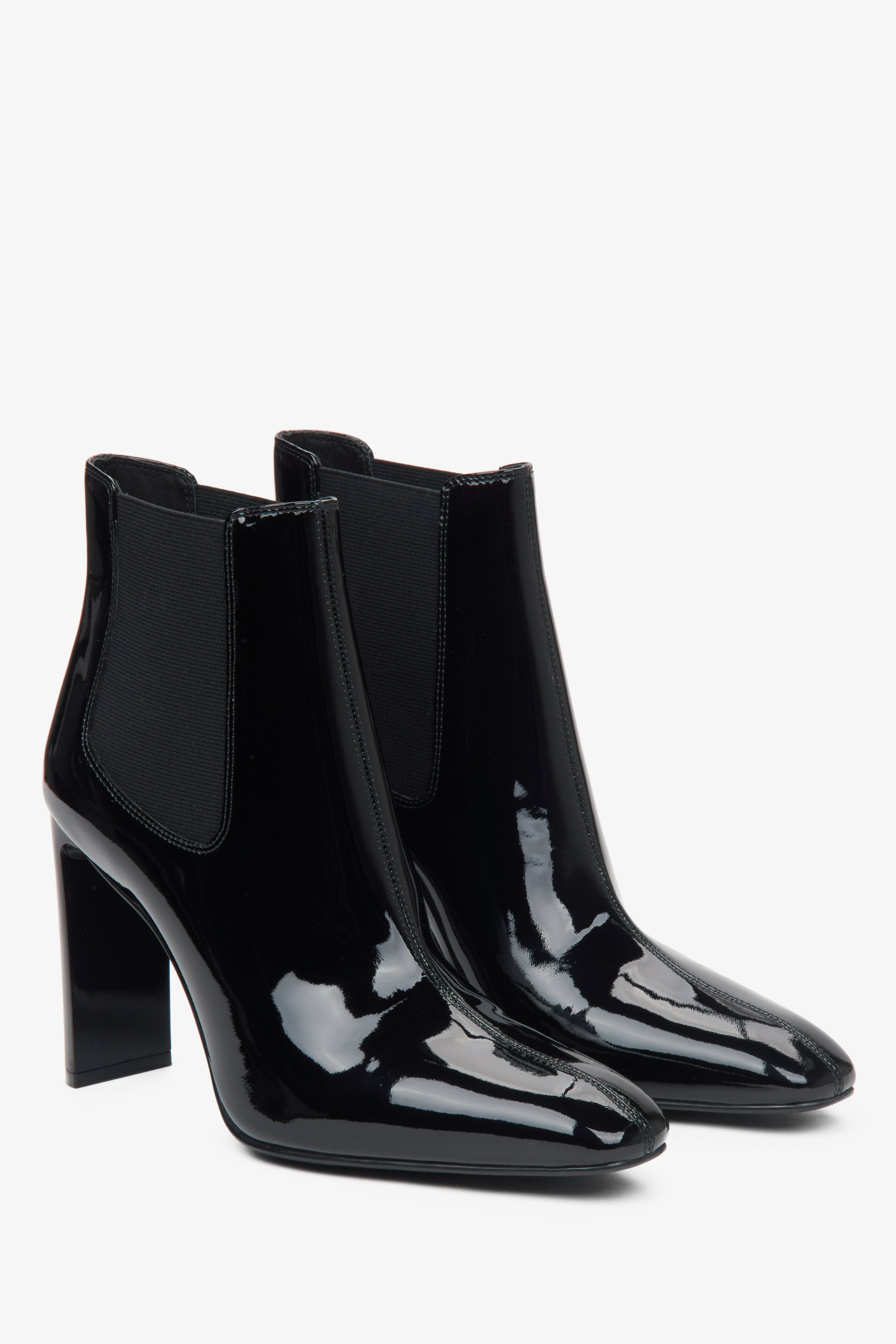 Elegant black ankle boots made of patent genuine leather with a high block heel from Estro - close-up of the toe and side line of the shoes.