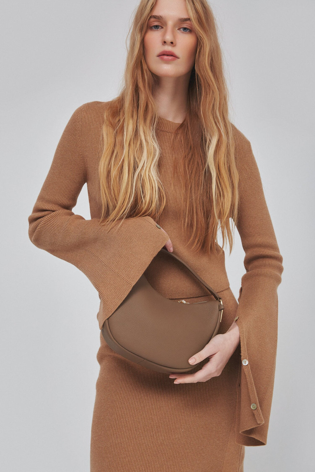 Brown crescent shaped handbag made of genuine leather by Estro - presentation on a model.