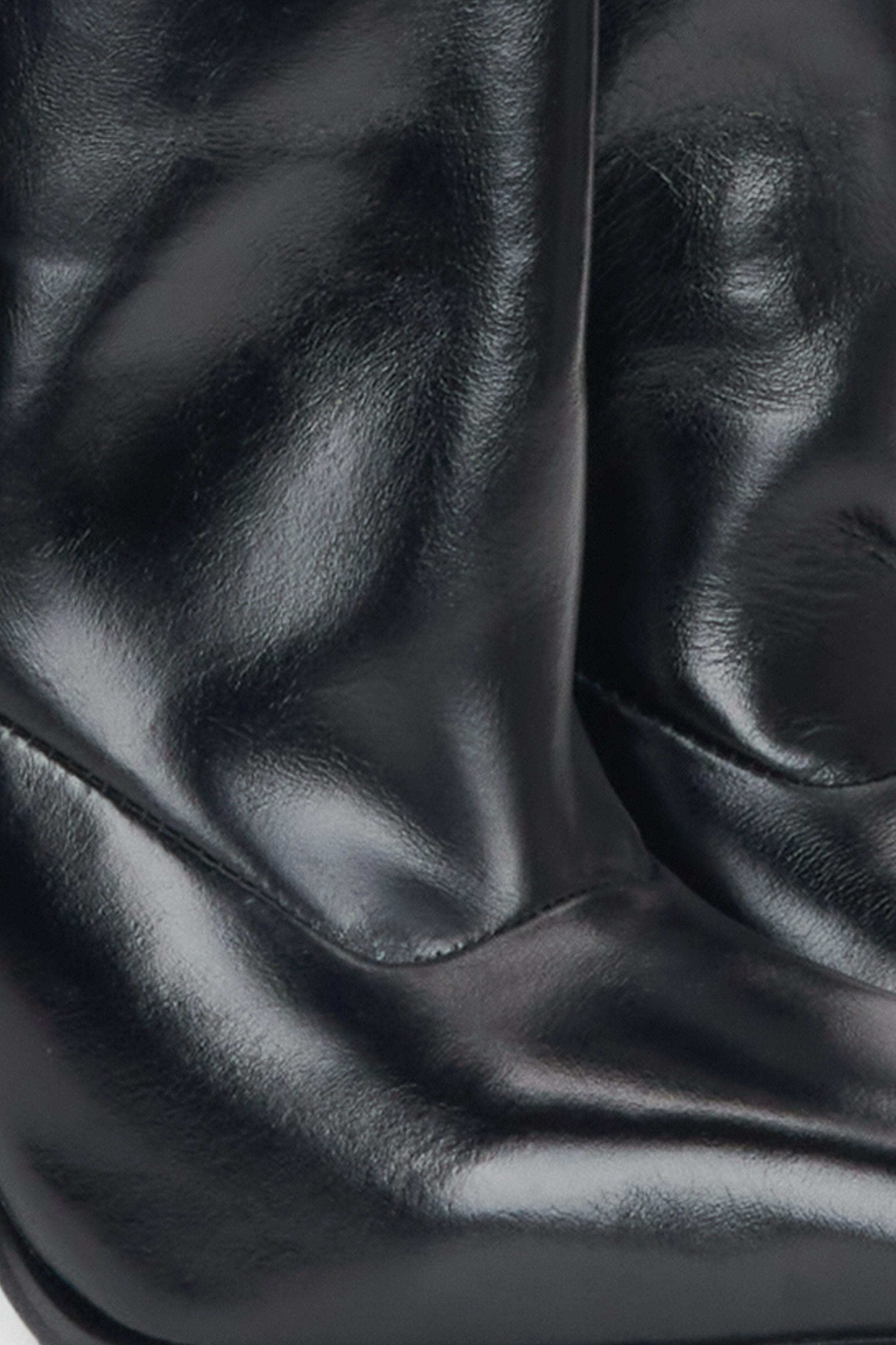 Estro black patent leather stiletto boots with a loose shaft - close-up of the leather texture.