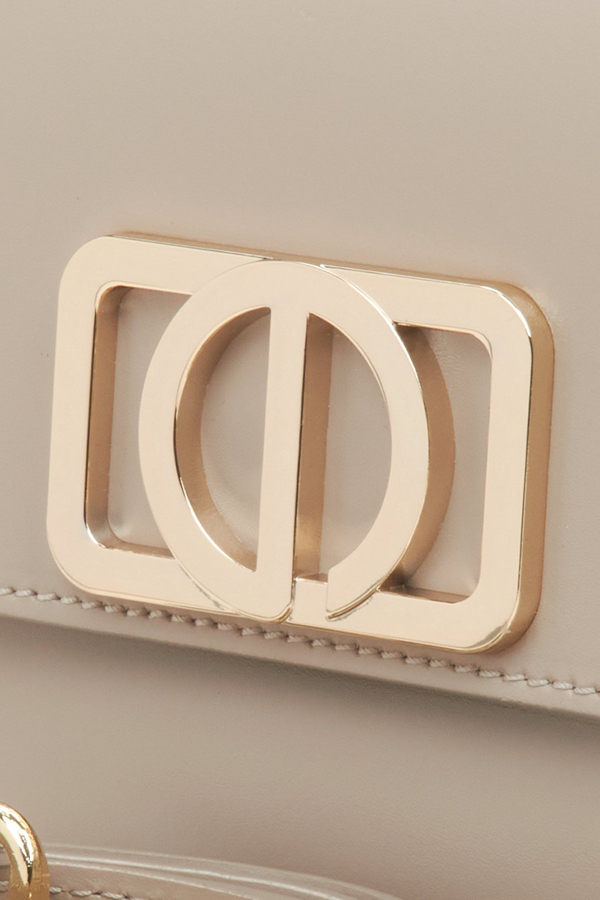 Feminine handbag in beige, compact in size - close-up on the detail.