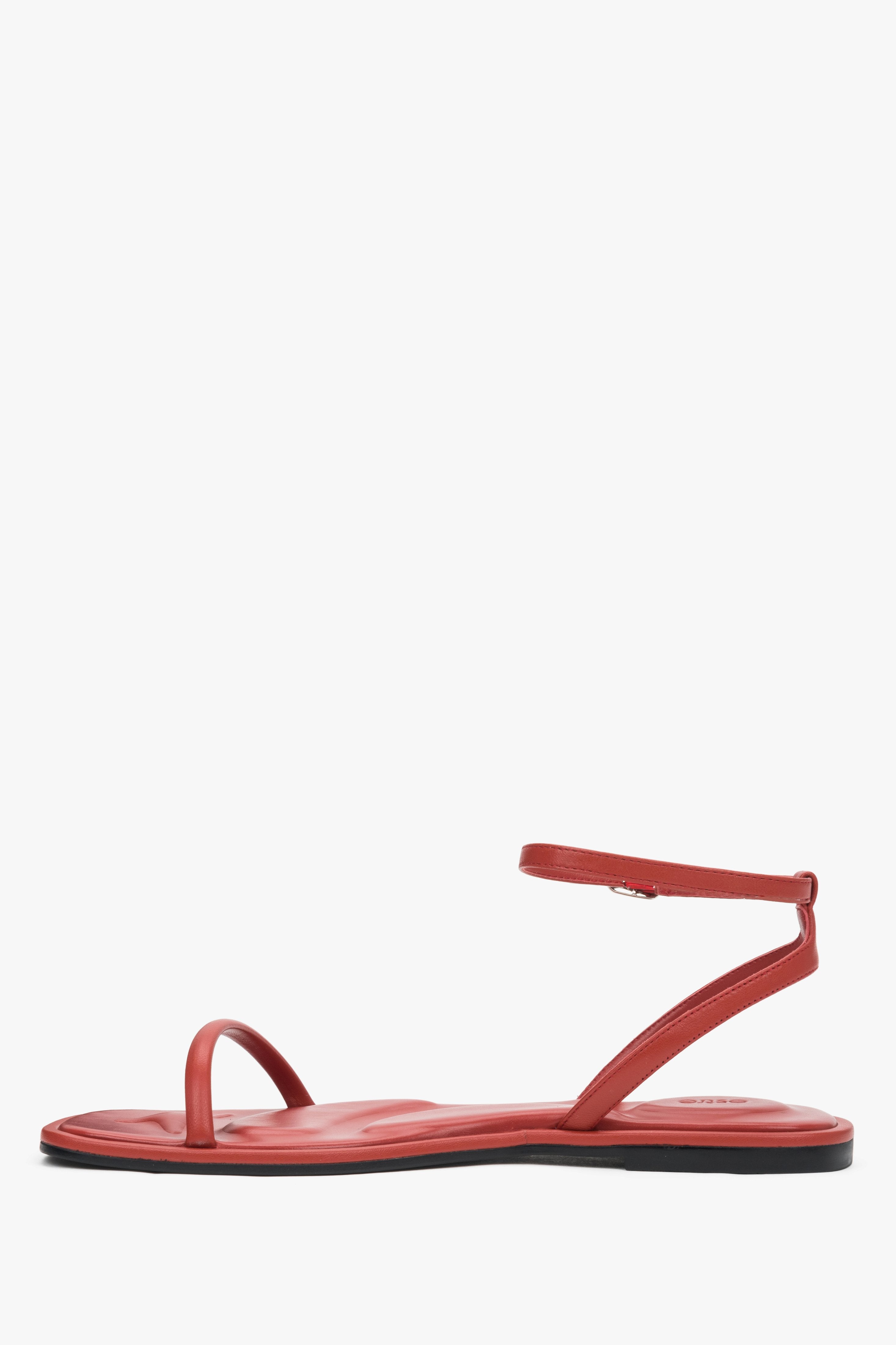 Red leather flat sandals with a silver buckle, summer style.