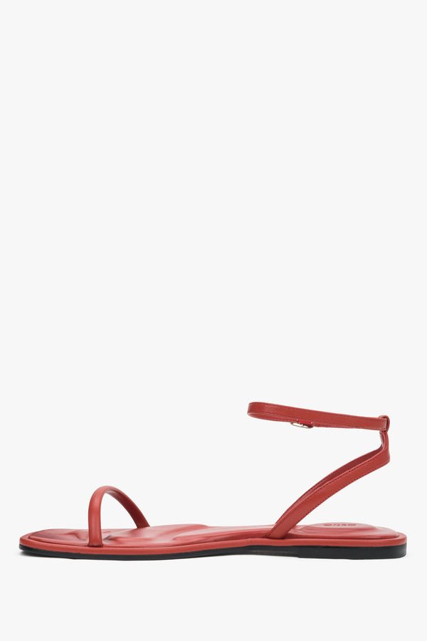 Red leather flat sandals with a silver buckle, summer style.