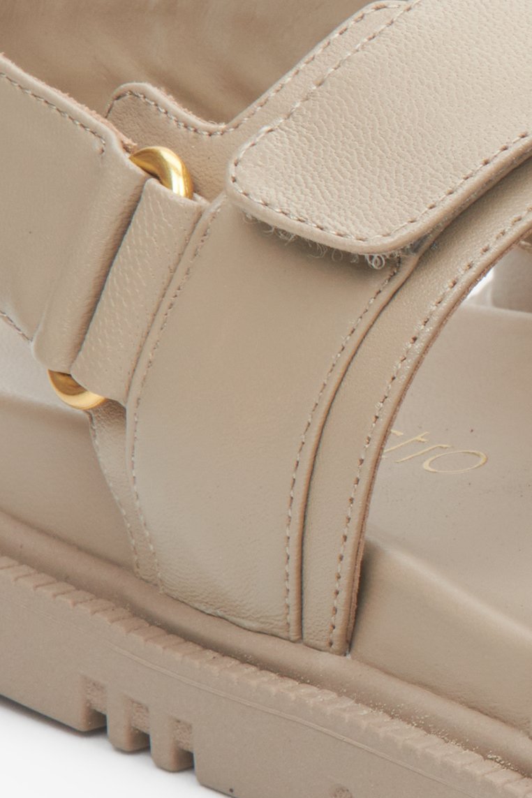 Women's beige leather comfortable sole sandals with golden elements - close-up on the details.