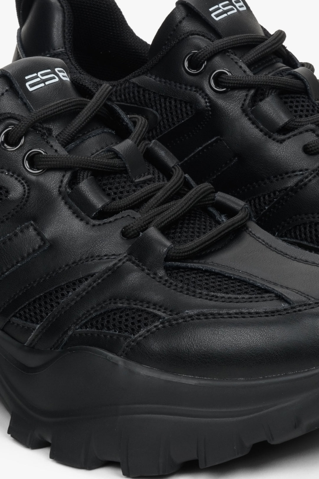 Women's black sneakers made of genuine leather - close-up of the stitching system and shoe details.