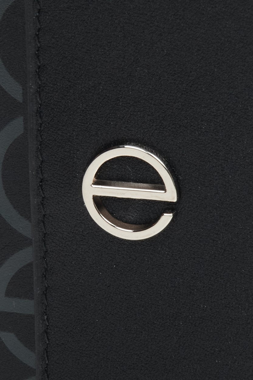 Women's leather tri-fold wallet with silver accents by Estro - close-up on the emblem.