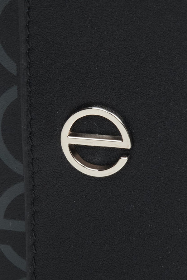 Women's leather tri-fold wallet with silver accents by Estro - close-up on the emblem.