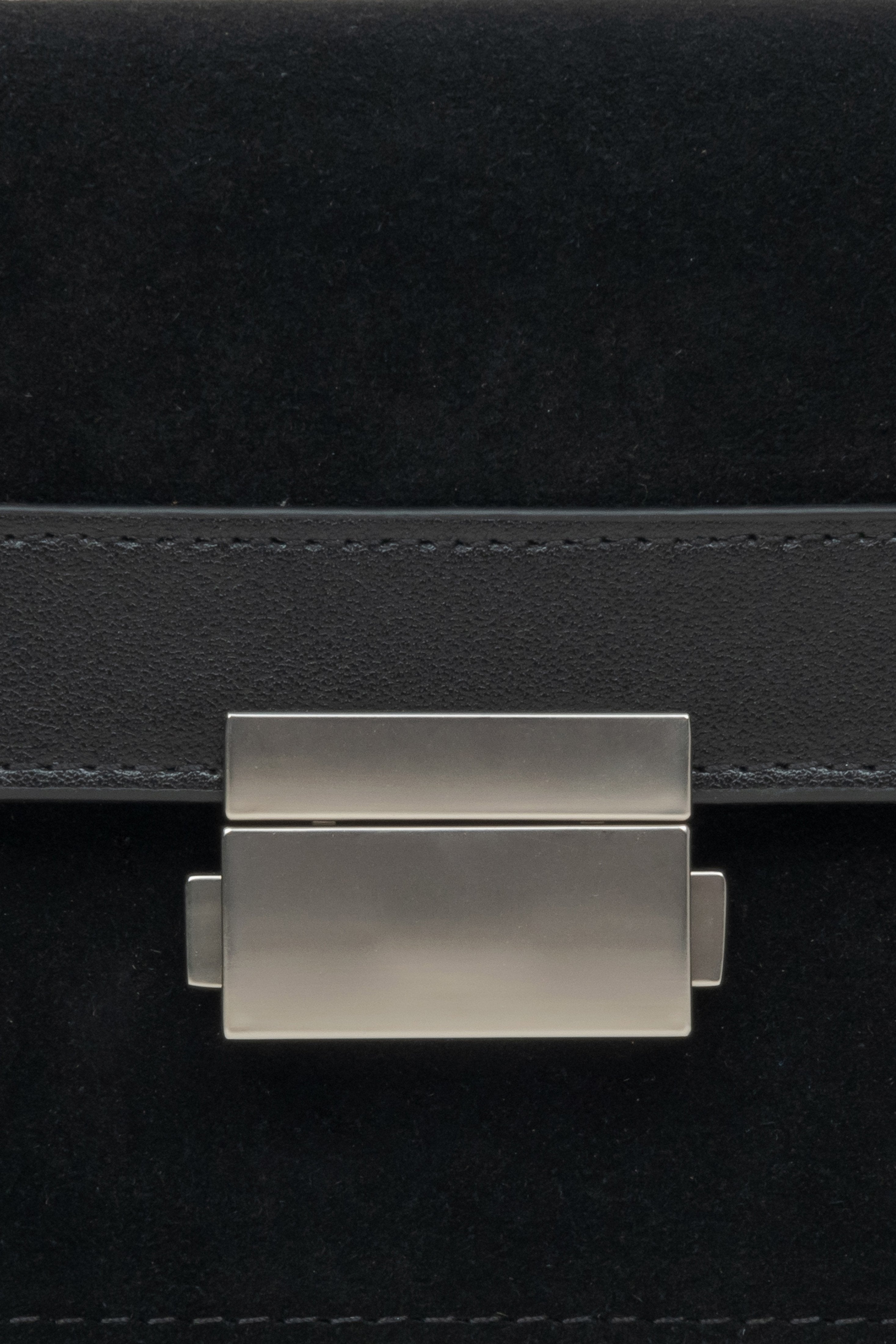 Compact women's handbag made of leather and velour in black - close-up of the detail.