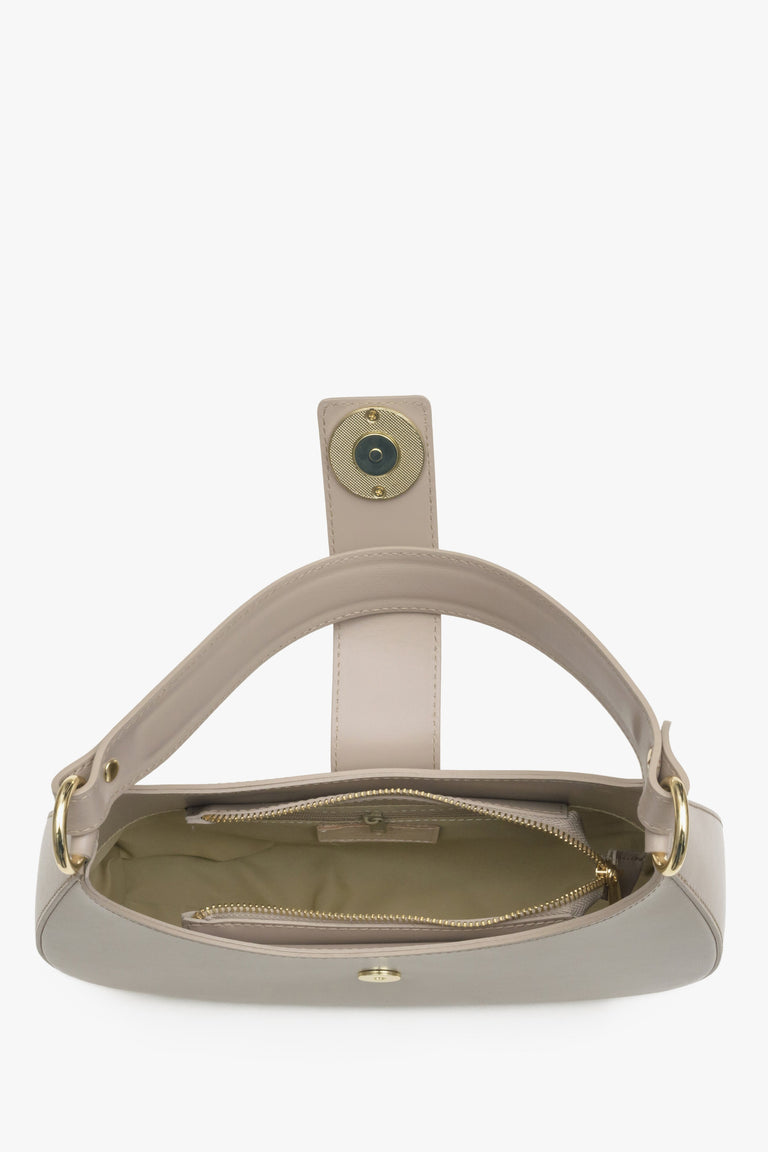 Interior presentation of a beige leather baguette-style women's handbag.