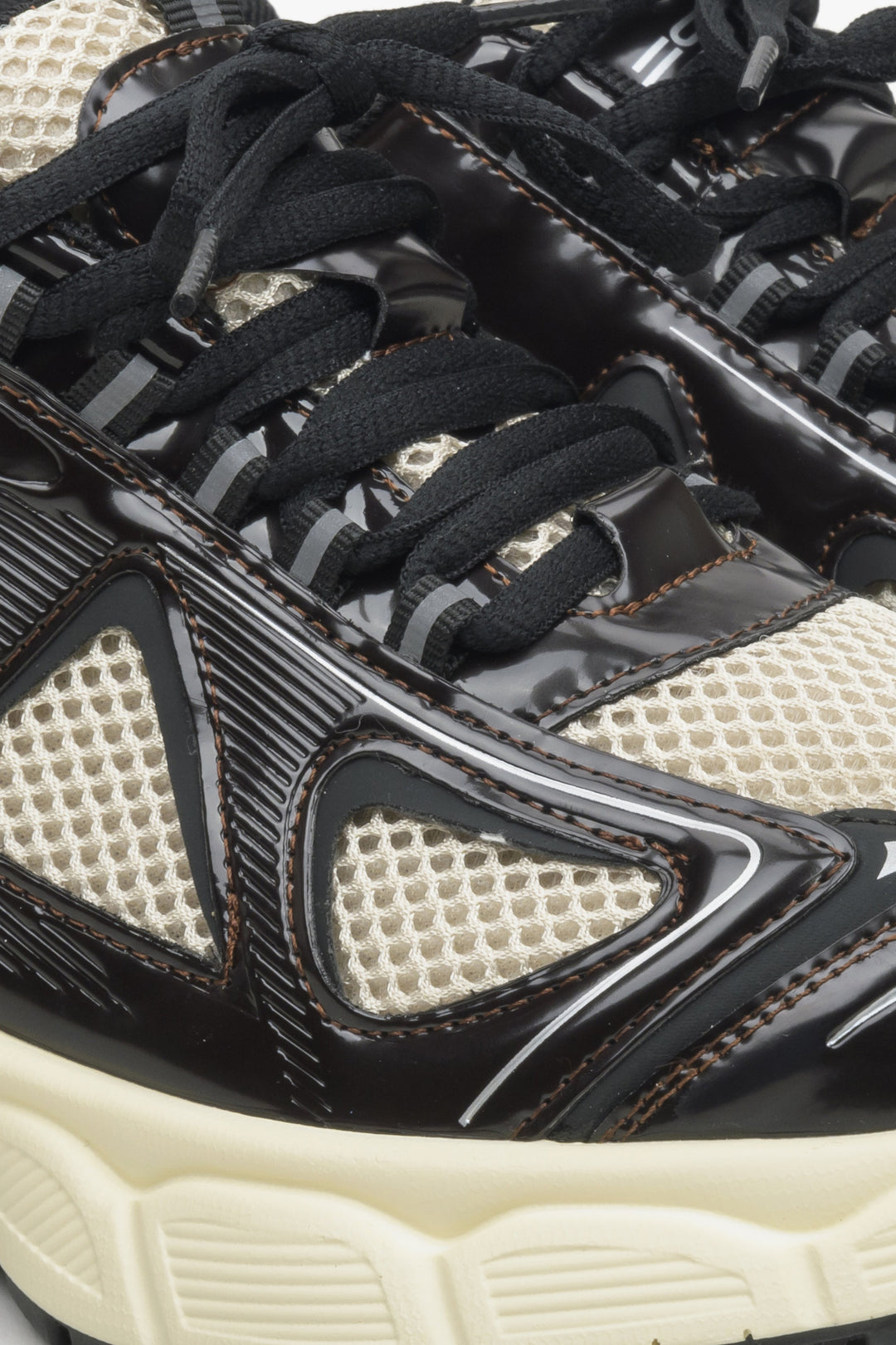 Women's black and beige sneakers with a flexible platform - close-up on the lacing line of the shoe.