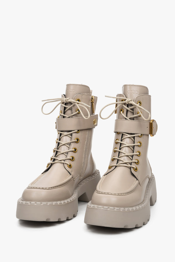 Leather women's beige Estro boots with a decorative strap and gold embellishments - close-up on the toe and lacing system.