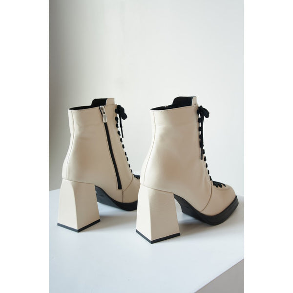 Women's beige ankle boots made of genuine leather with a black sole.