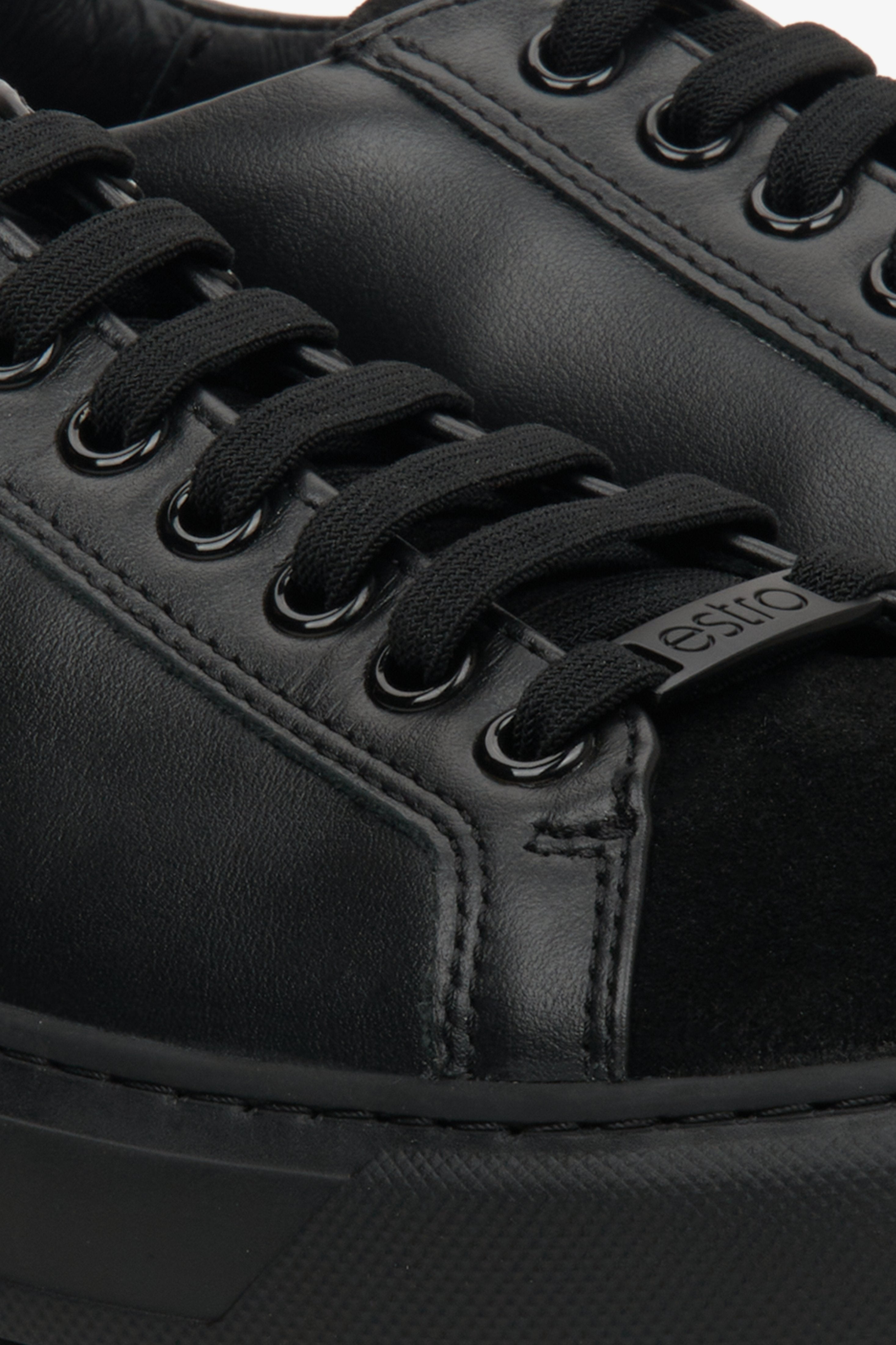 Women's black sneakers made of genuine leather and velour - close-up on the lacing system.