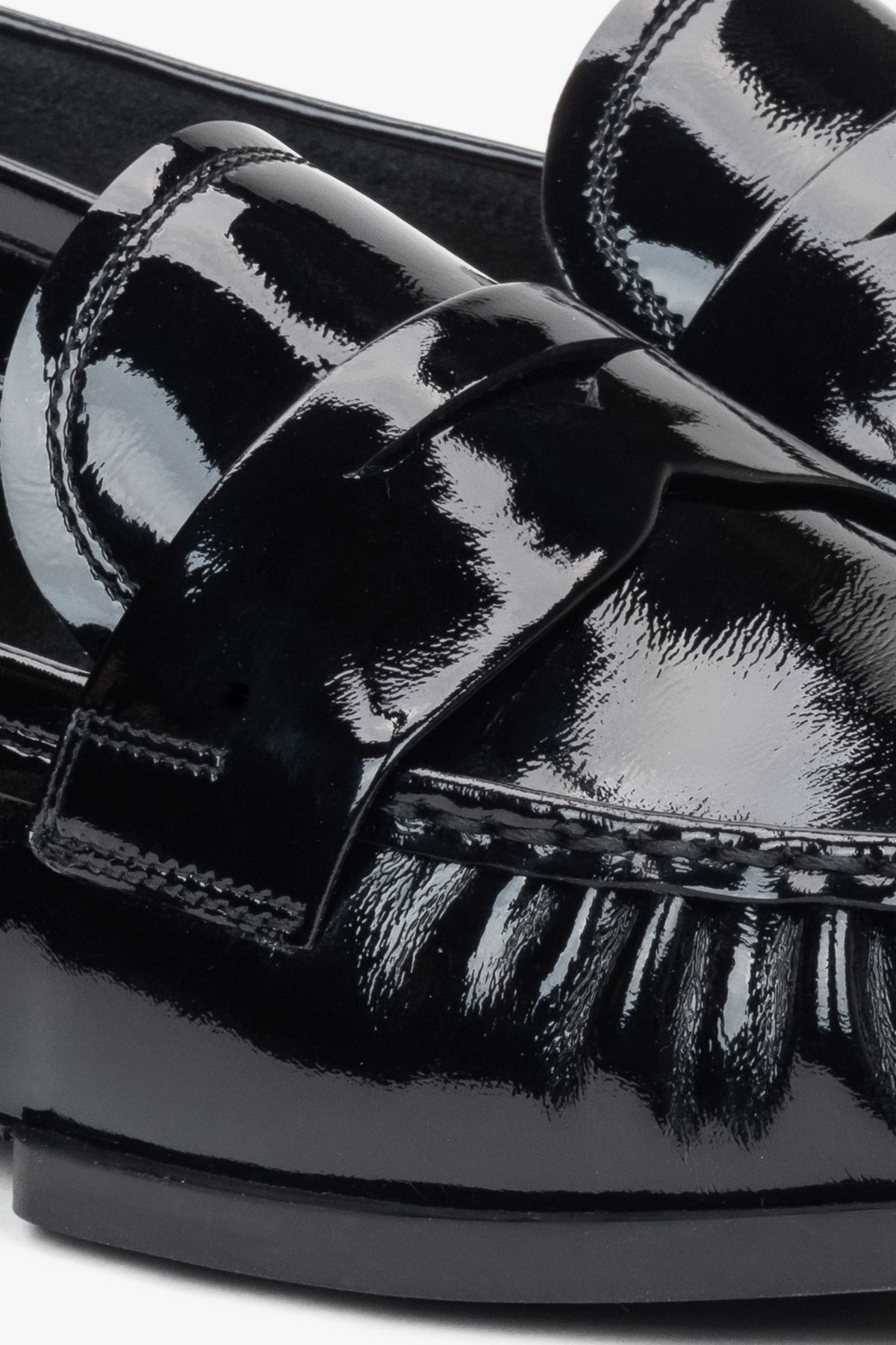 Stylish women's loafers made of black patent genuine leather – close-up on the details.
