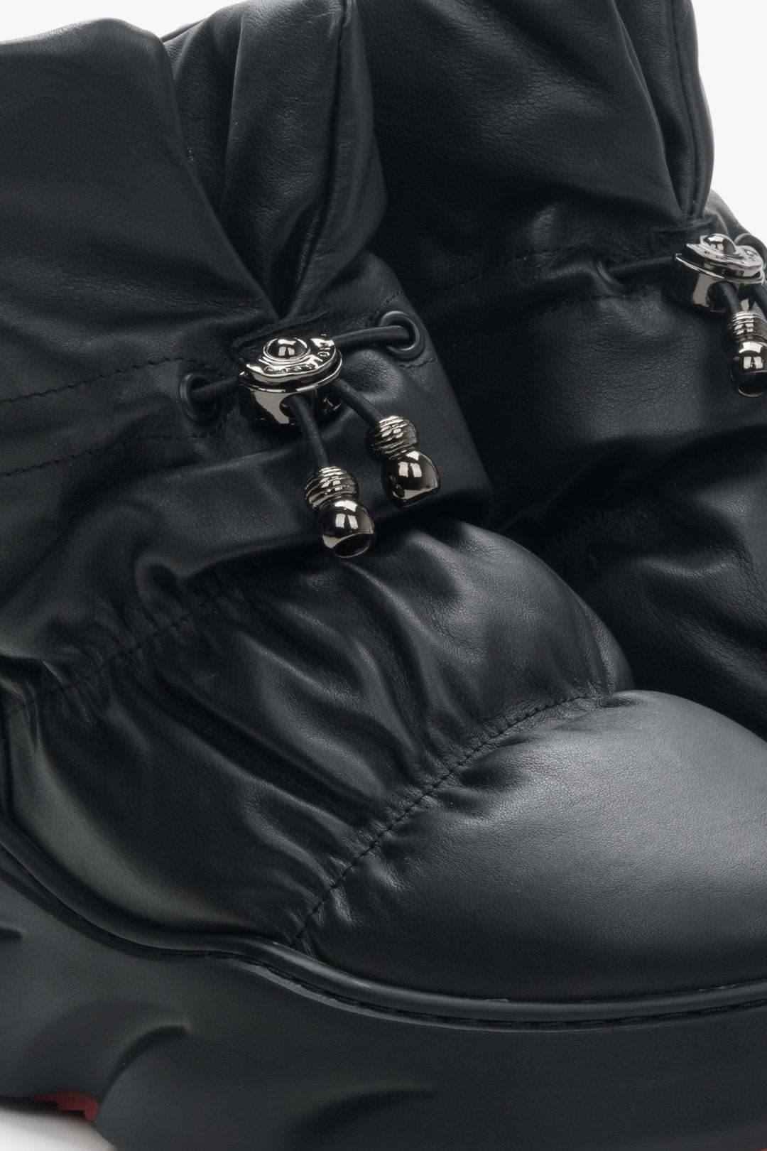 Women's black winter snow boots with leather and fur - close-up on golden details.