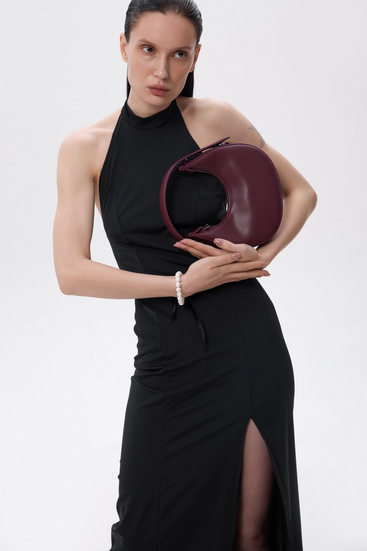 Women's crescent-shaped handbag in a trendy burgundy color, offered by Estro.