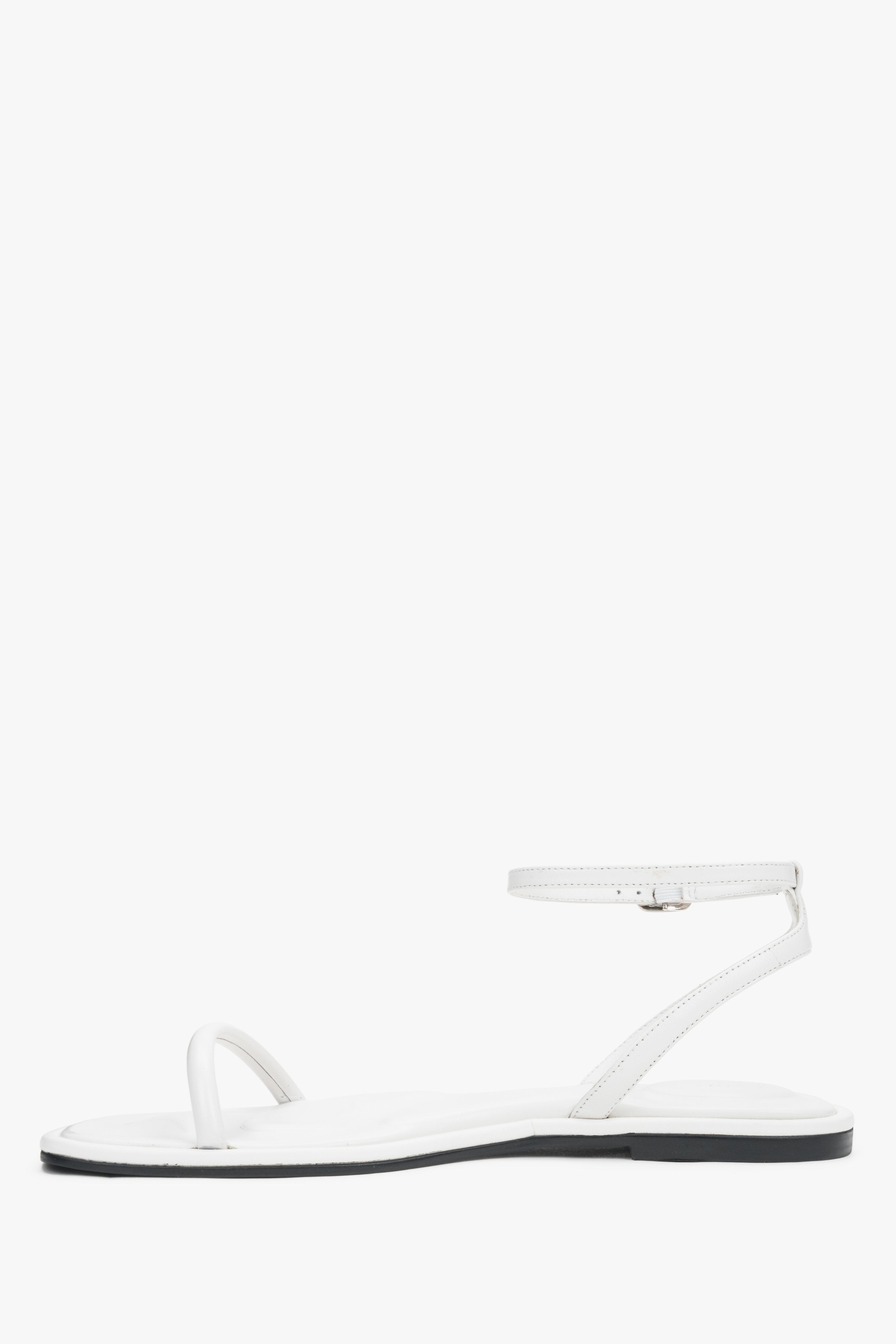 White leather flat sandals with a silver buckle, summer style.