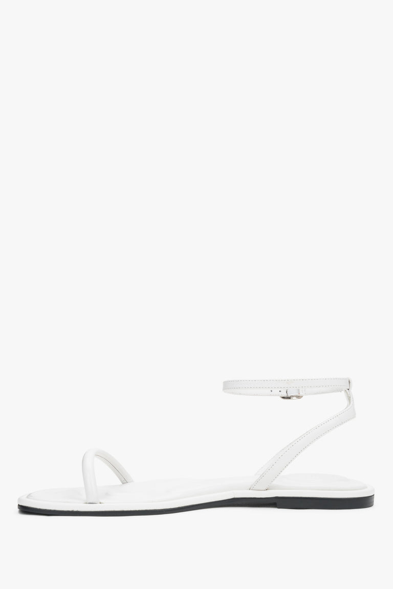 White leather flat sandals with a silver buckle, summer style.