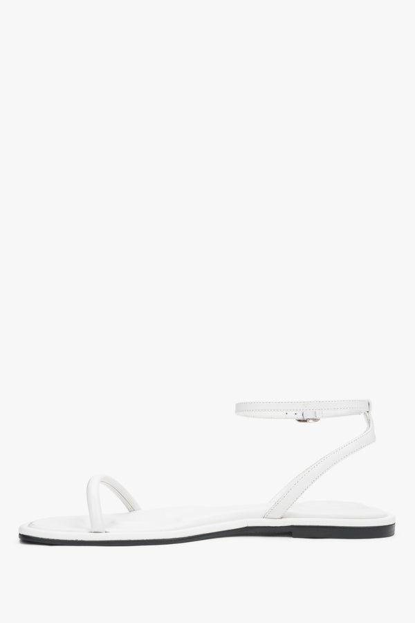 White leather flat sandals with a silver buckle, summer style.