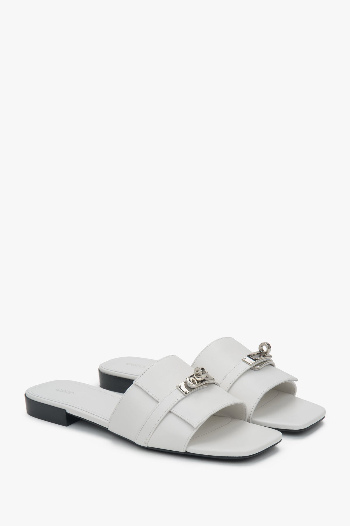 Elegant white Estro women's slide sandals, adorned with a silver embellishment, perfect for everyday wear, featuring a comfortable flat heel.
