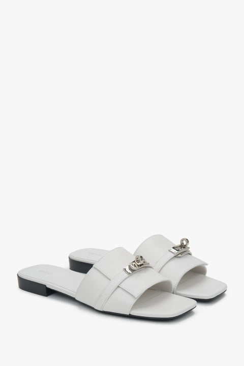 Elegant white Estro women's slide sandals, adorned with a silver embellishment, perfect for everyday wear, featuring a comfortable flat heel.