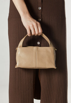 Women's beige handbag by Estro - presented in the model’s hand.