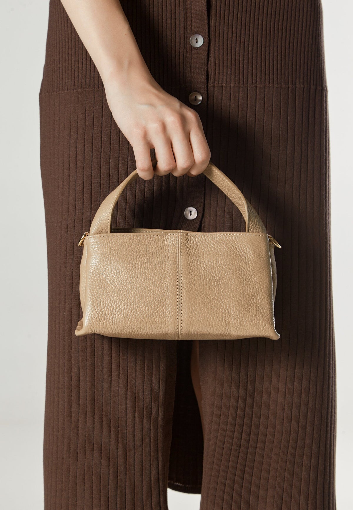Women's beige handbag by Estro - presented in the model’s hand.