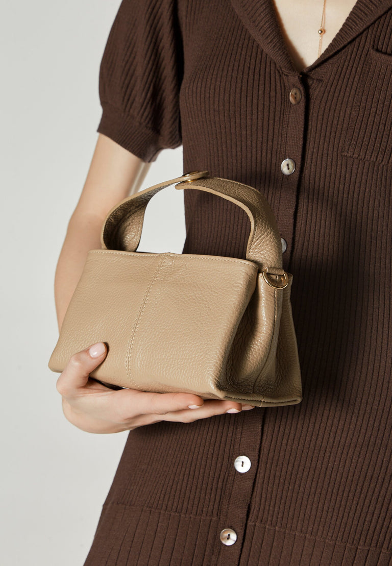 Handy women's beige handbag - presented in the model’s hand.
