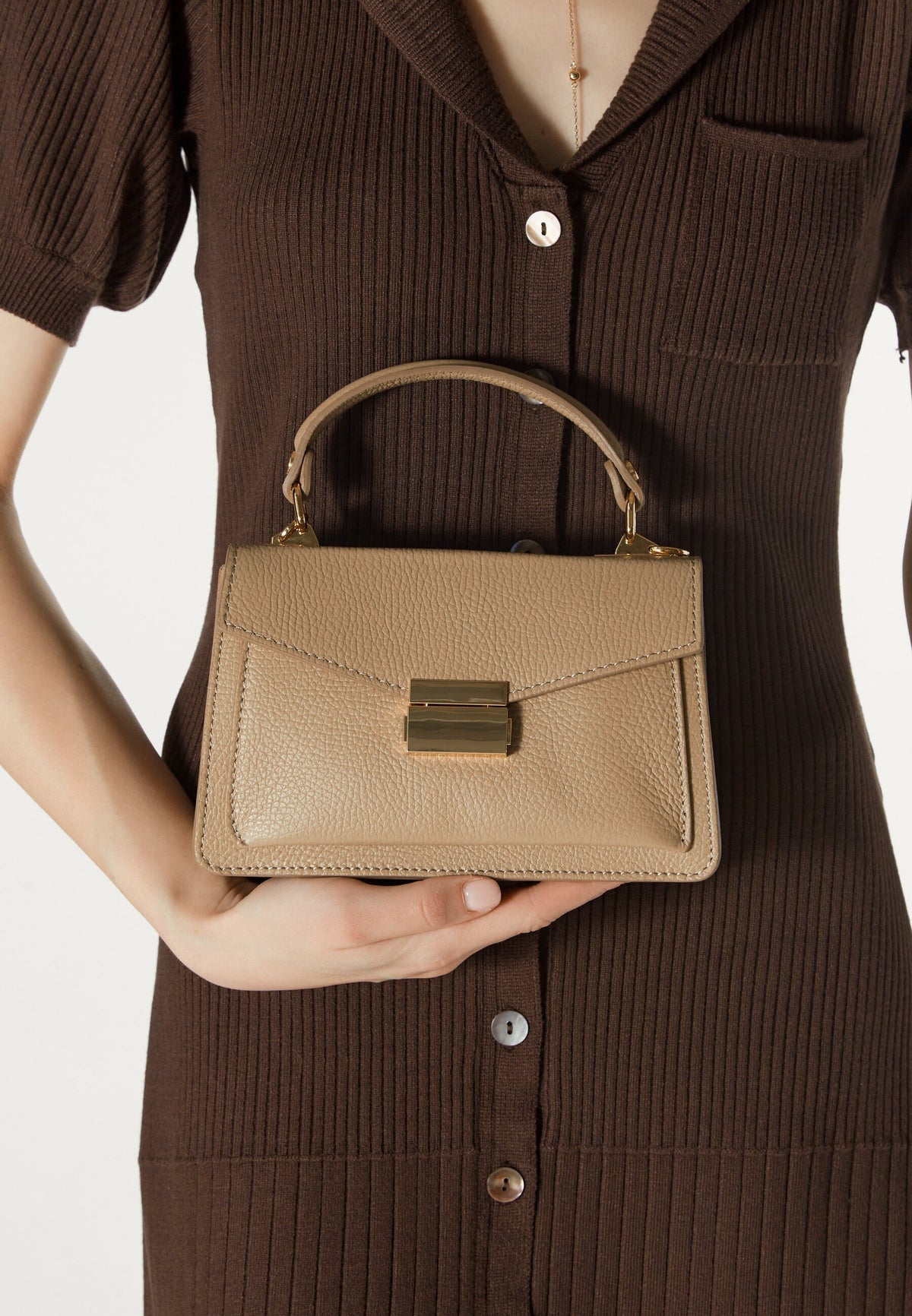 Women's small beige  handbag in the shape of a case - model presentation.