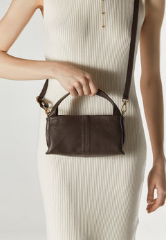 Women's dark brown handbag by Estro - presented in the model’s hand.